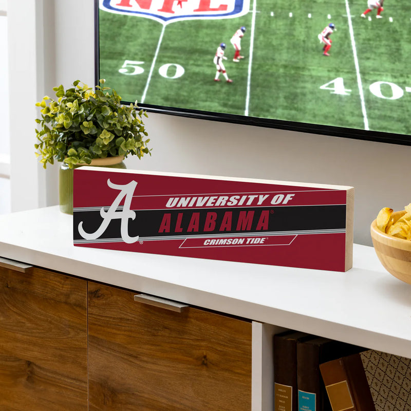 University of Alabama sign on a TV stand with a football game on screen