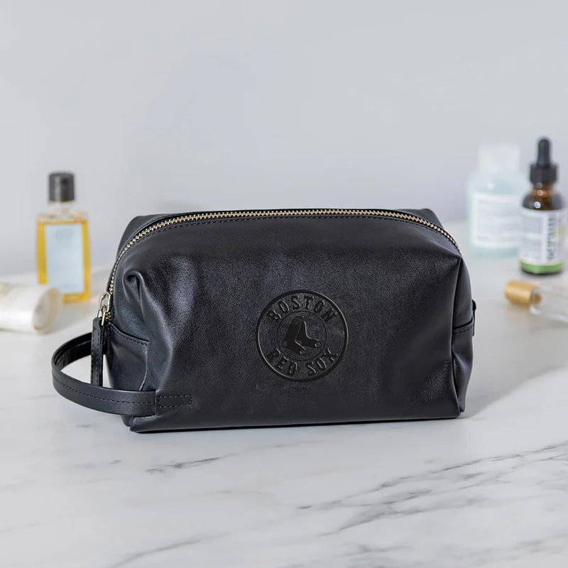 Black leather toiletry bag with Boston Red Sox logo on a marble surface