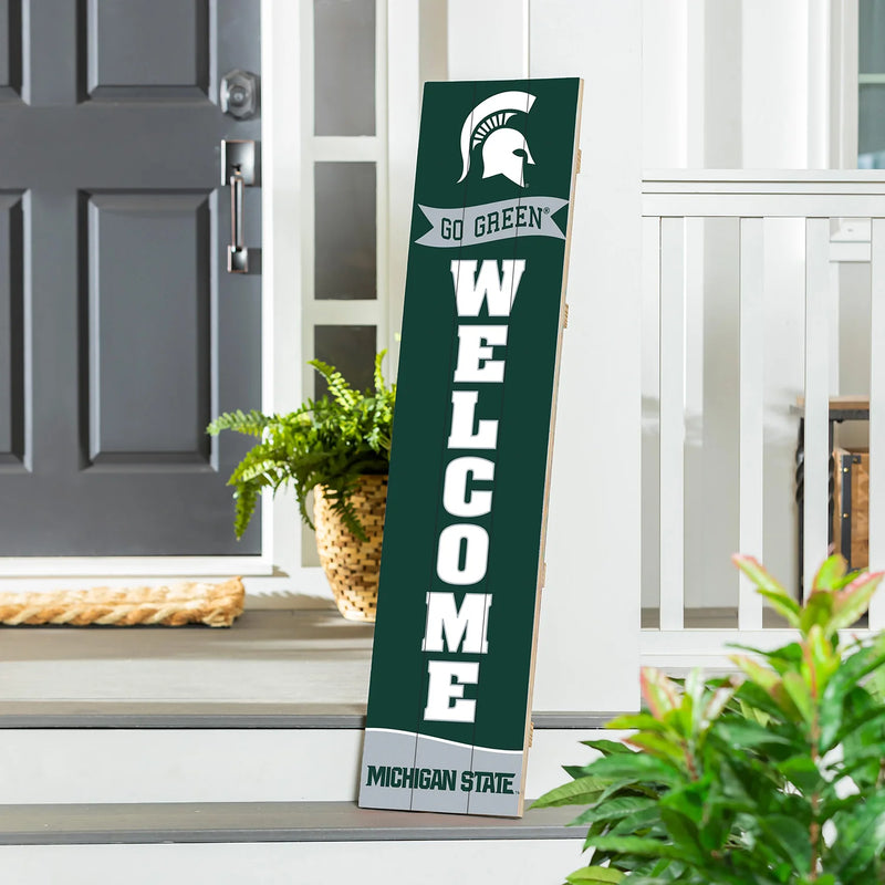 Michigan State welcome sign on a porch with plants and a door in the background