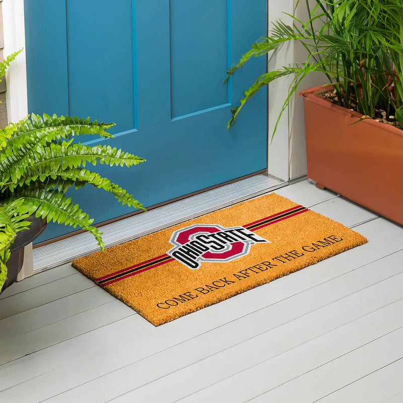 Doormat with an Ohio State logo on a wooden floor in front of a blue door.